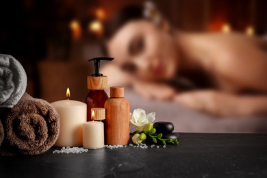 Image of Spa therapy. Woman lying on massage table and composition with body care products in salon, selective focus