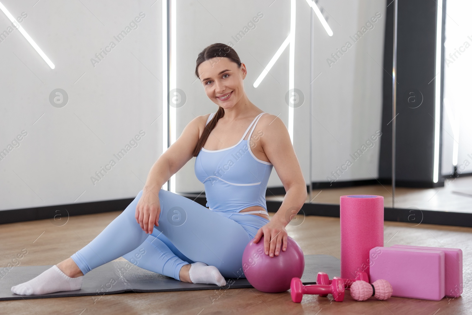 Woman with medicine ball and other sports equipment in fitness studio Photo of Woman with medicine ball and other sports equipment in fitness studio