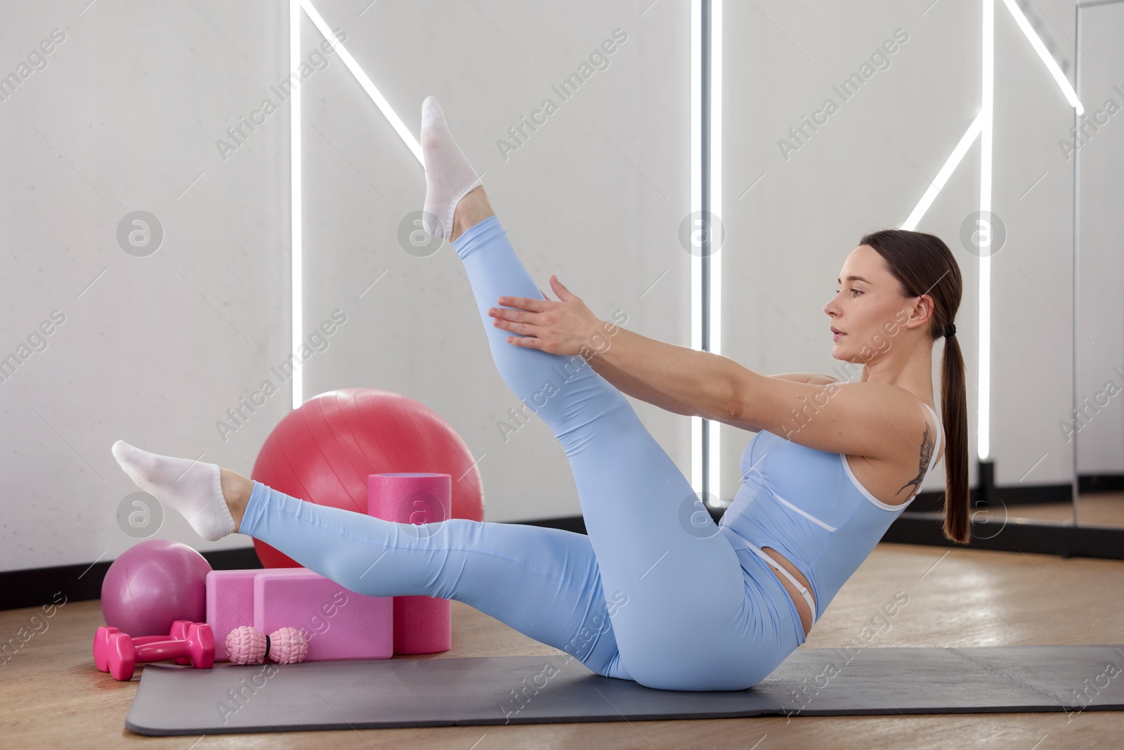 Woman exercising on mat in fitness studio Photo of Woman exercising on mat in fitness studio