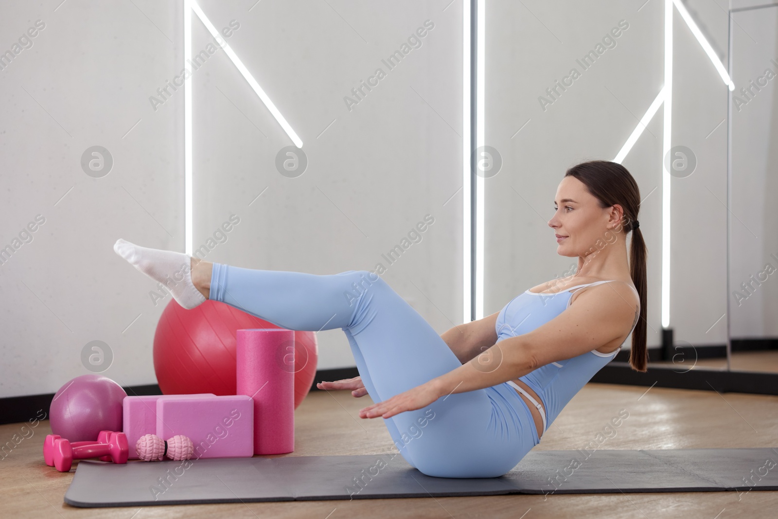 Woman exercising on mat in fitness studio Photo of Woman exercising on mat in fitness studio