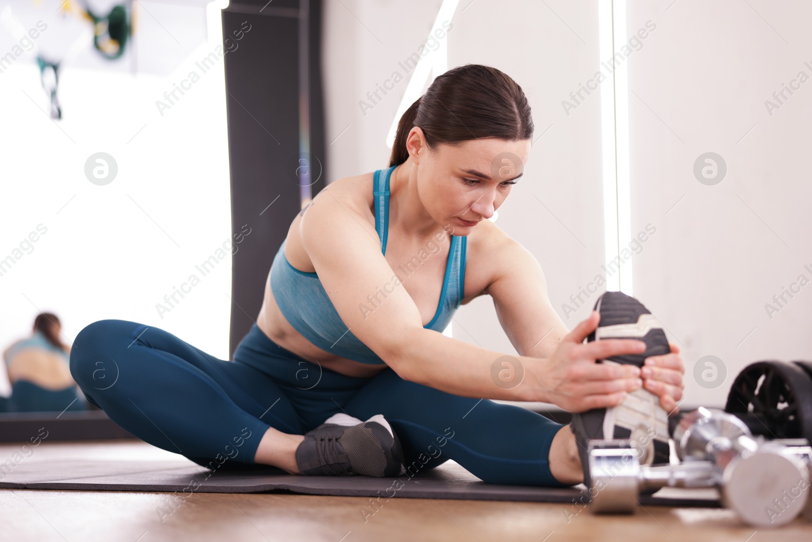 Woman stretching on mat in fitness studio Photo of Woman stretching on mat in fitness studio
