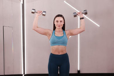 Photo of Woman exercising with dumbbells in fitness studio