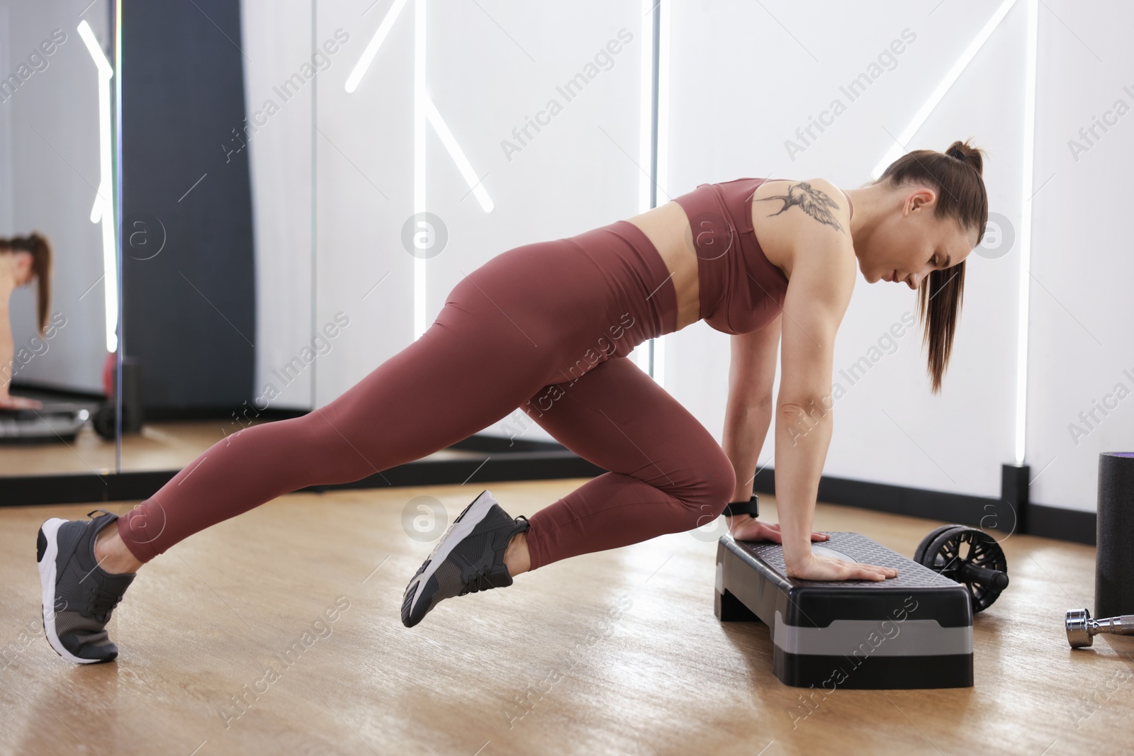 Woman exercising with step platform in fitness studio Photo of Woman exercising with step platform in fitness studio