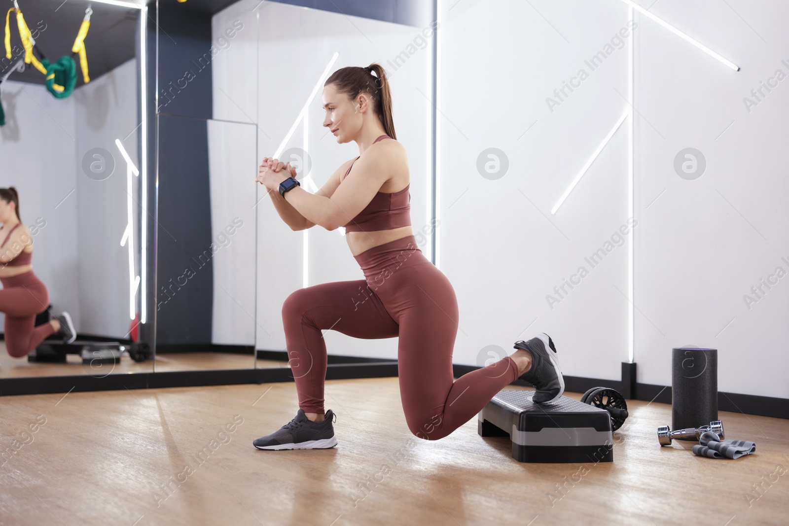 Woman exercising with step platform in fitness studio Photo of Woman exercising with step platform in fitness studio