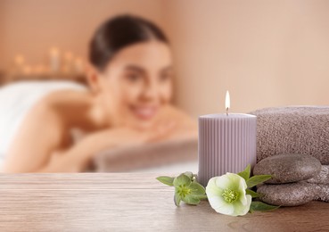 Image of Spa therapy. Woman lying on massage table and composition with candle and stones in salon, selective focus