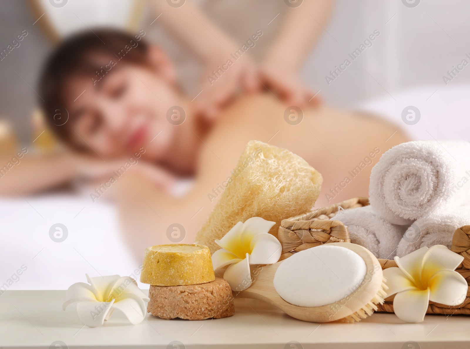 Spa therapy. Woman receiving massage on table and different body care products in salon, selective focus Image of Spa therapy. Woman receiving massage on table and different body care products in salon, selective focus
