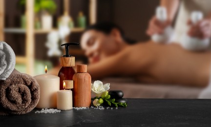 Image of Spa therapy. Woman receiving massage on table and composition with body care products in salon, selective focus