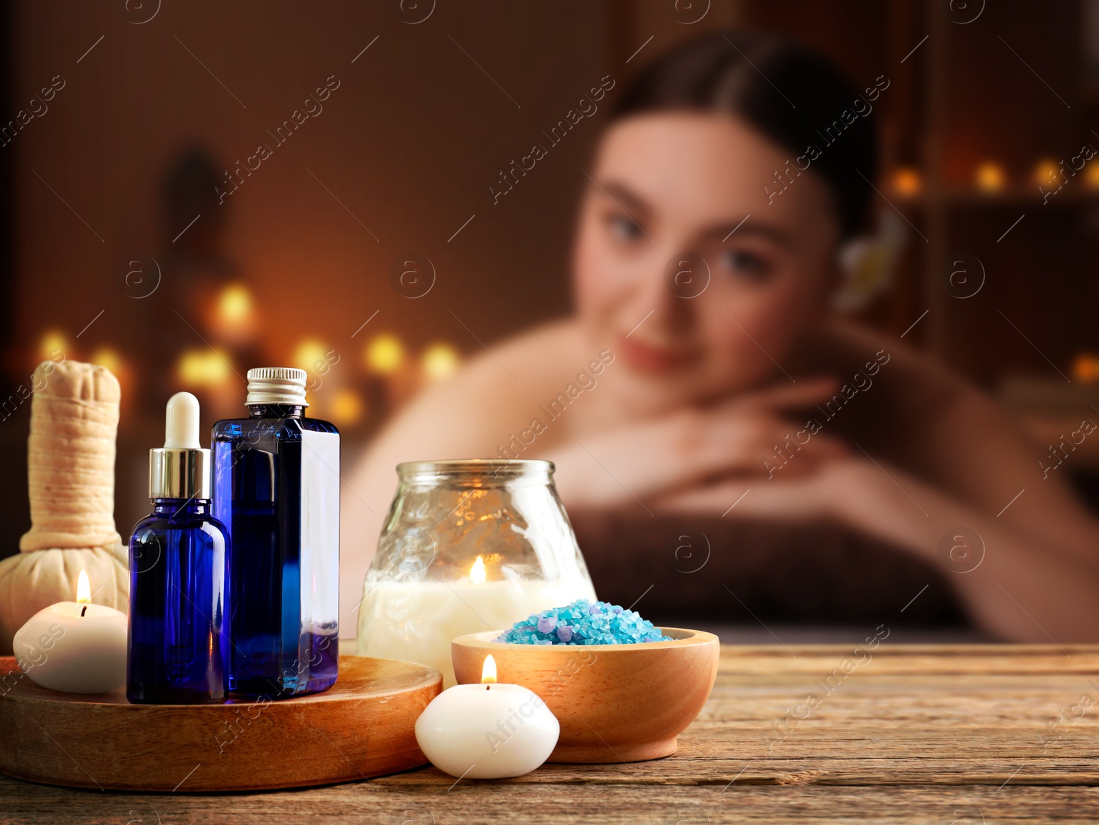 Spa therapy. Woman lying on massage table and composition with body care products and candles in salon, selective focus Image of Spa therapy. Woman lying on massage table and composition with body care products and candles in salon, selective focus