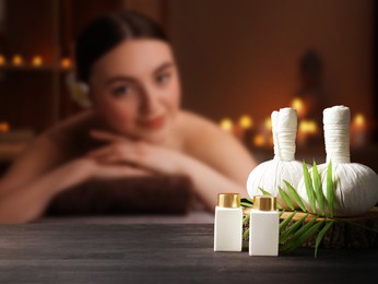 Image of Spa therapy. Woman lying on massage table and composition with body care products and herbal bags in salon, selective focus