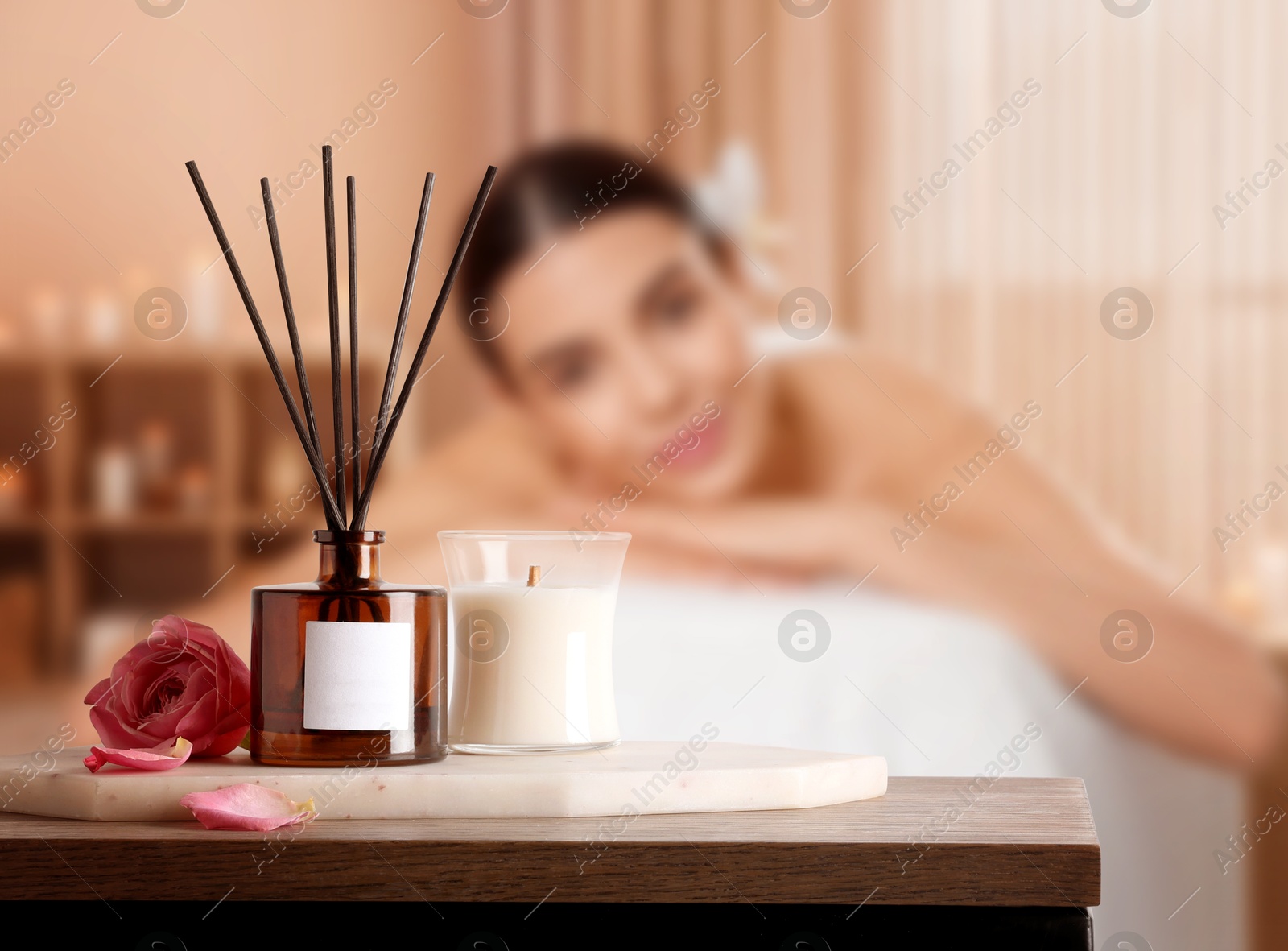 Spa therapy. Woman lying on massage table and composition with reed air freshener in salon, selective focus Image of Spa therapy. Woman lying on massage table and composition with reed air freshener in salon, selective focus
