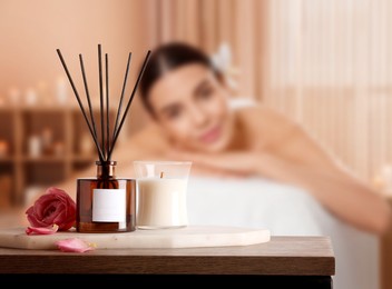Image of Spa therapy. Woman lying on massage table and composition with reed air freshener in salon, selective focus