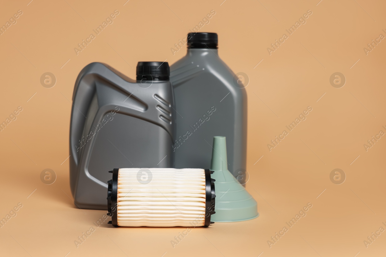 Motor oil in plastic canisters, filter and funnel on beige background, space for text Photo of Motor oil in plastic canisters, filter and funnel on beige background, space for text