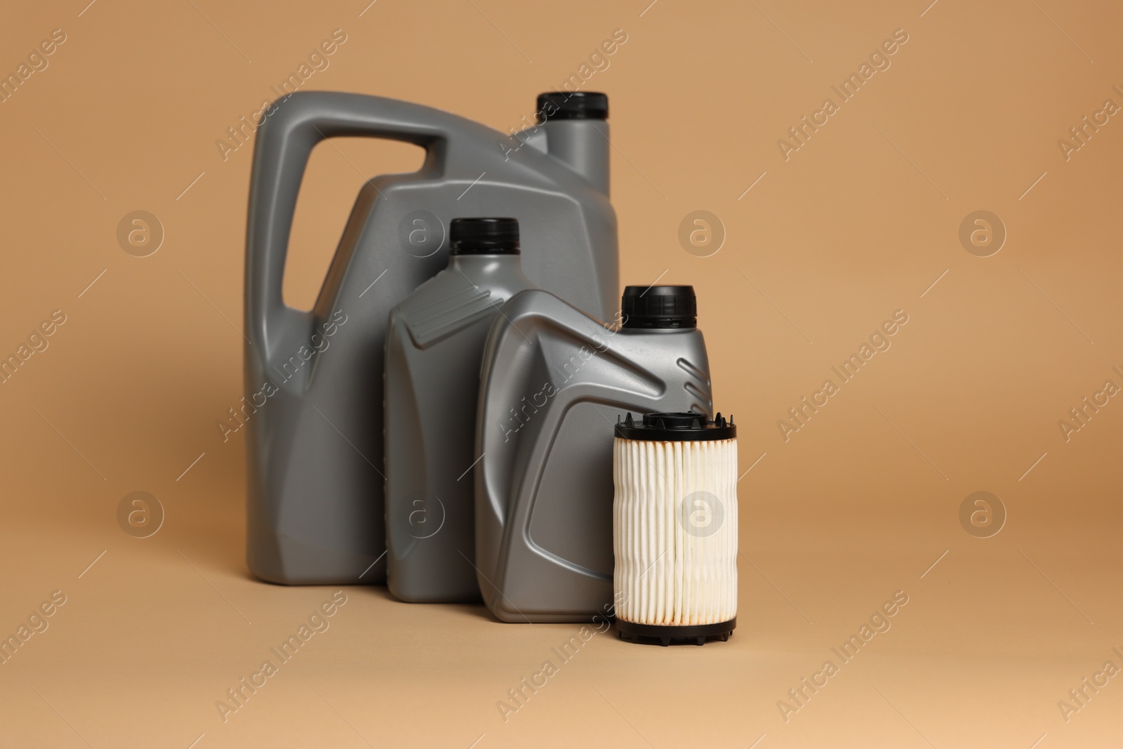 Motor oil in plastic canisters and filter on beige background, space for text Photo of Motor oil in plastic canisters and filter on beige background, space for text