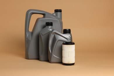 Photo of Motor oil in plastic canisters and filter on beige background, space for text