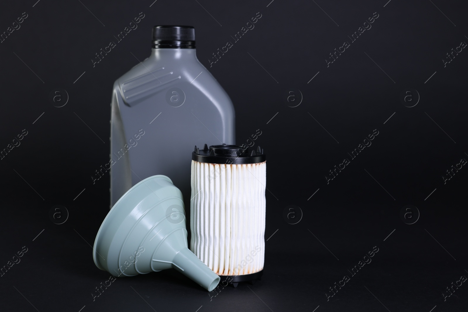Motor oil in plastic canister, filter and funnel on black background, space for text Photo of Motor oil in plastic canister, filter and funnel on black background, space for text