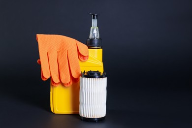 Photo of Motor oil in plastic canister, gloves and filter on dark grey background, space for text