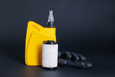 Photo of Motor oil in plastic canister, gloves and filter on dark grey background