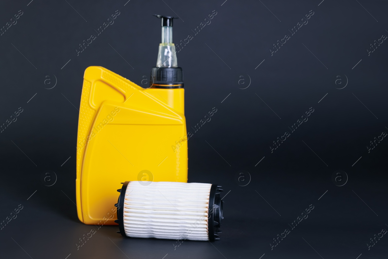 Motor oil in plastic canister and filter on dark grey background, space for text Photo of Motor oil in plastic canister and filter on dark grey background, space for text