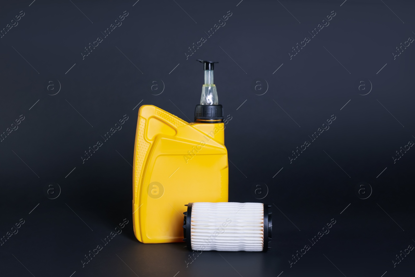 Motor oil in plastic canister and filter on dark grey background Photo of Motor oil in plastic canister and filter on dark grey background