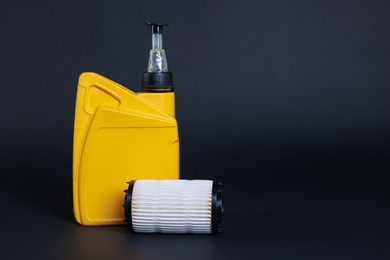 Photo of Motor oil in plastic canister and filter on dark grey background, space for text
