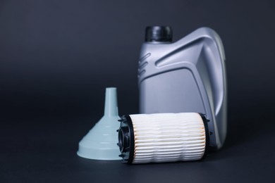 Photo of Motor oil in plastic canister, filter and funnel on dark grey background