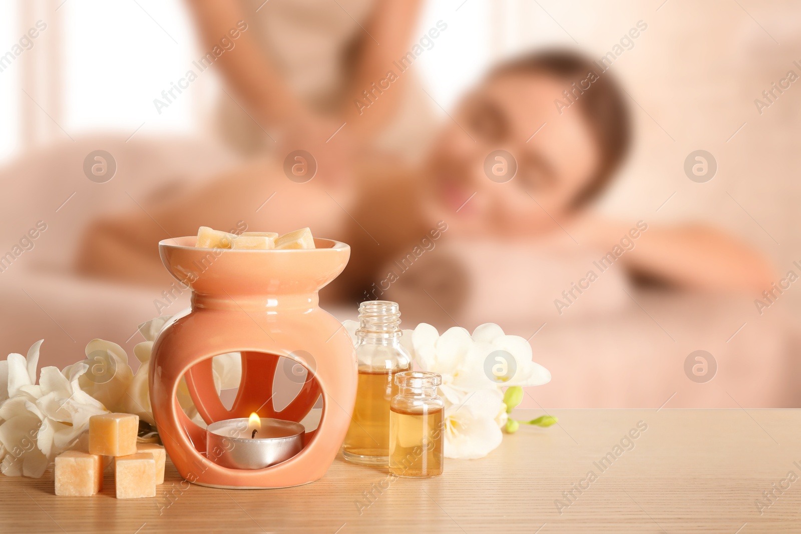 Image of Spa therapy. Woman receiving massage on table and composition with aroma lamp in salon, selective focus