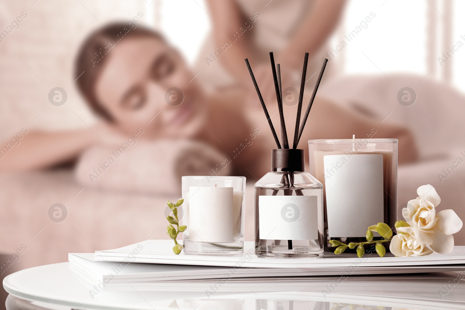 Spa therapy. Woman receiving massage on table and composition reed air freshener and scented candles in salon, selective focus Image of Spa therapy. Woman receiving massage on table and composition reed air freshener and scented candles in salon, selective focus