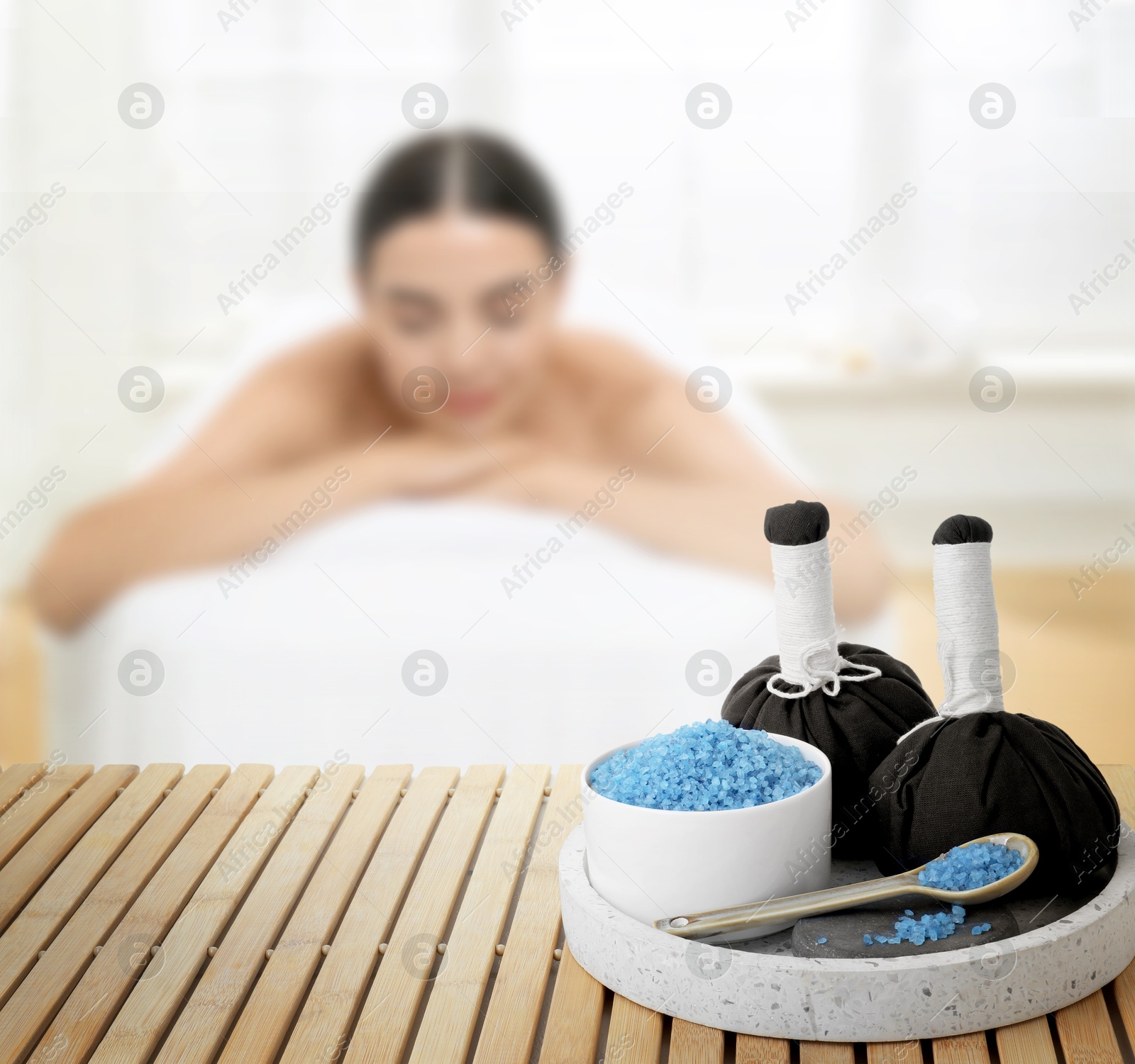 Spa therapy. Woman lying on massage table and composition with sea salt and herbal bags in salon, selective focus Image of Spa therapy. Woman lying on massage table and composition with sea salt and herbal bags in salon, selective focus