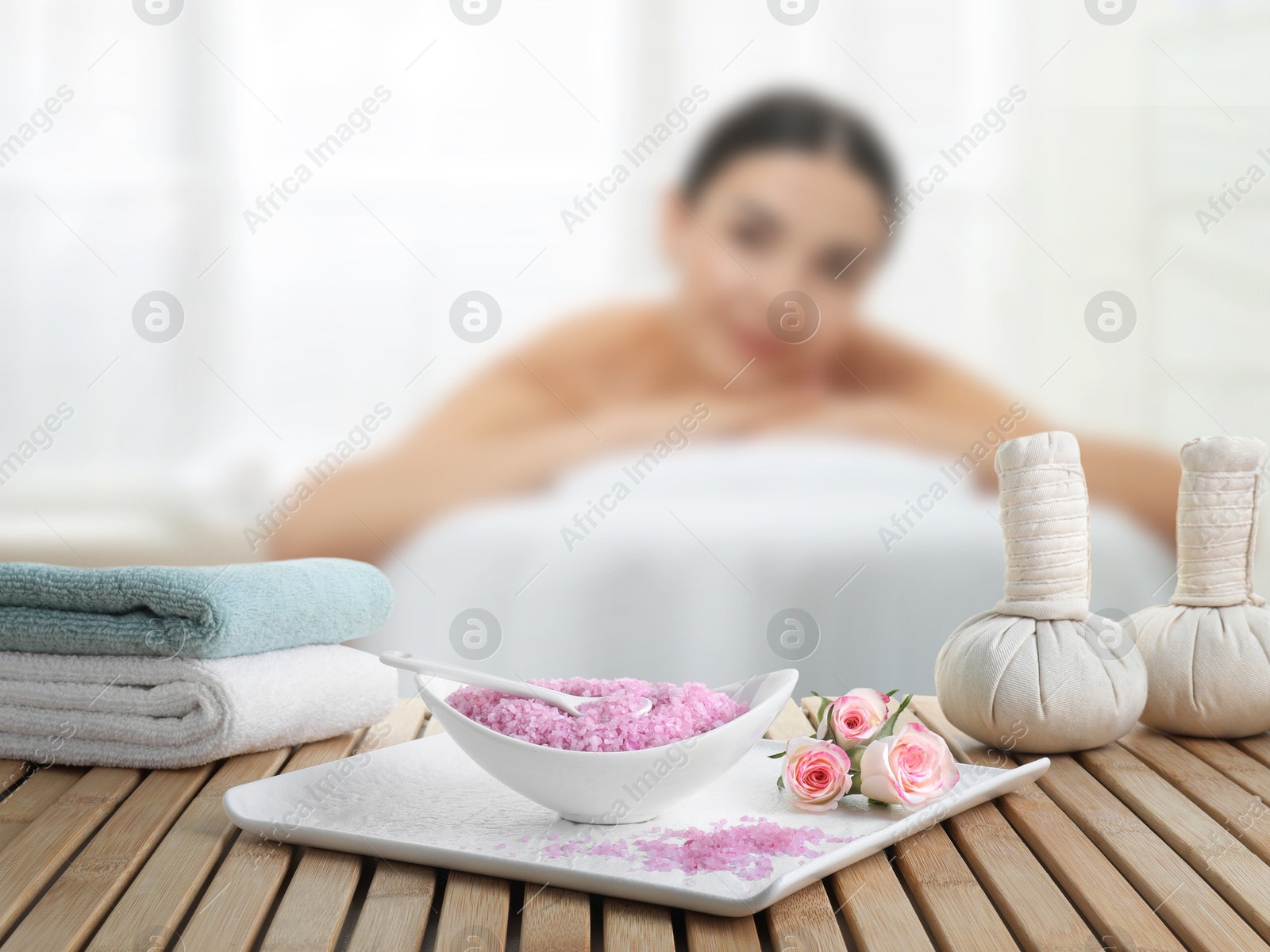 Spa therapy. Woman lying on massage table and composition with sea salt, herbal bags and towels in salon, selective focus Image of Spa therapy. Woman lying on massage table and composition with sea salt, herbal bags and towels in salon, selective focus