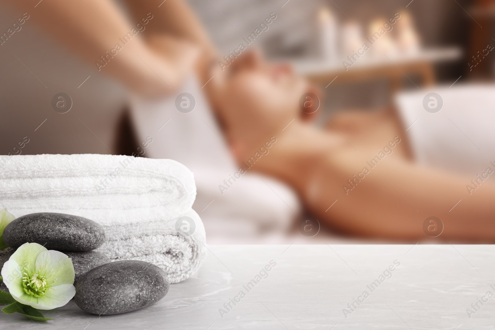 Spa therapy. Woman receiving massage on table and composition with stones and towels in salon, selective focus Image of Spa therapy. Woman receiving massage on table and composition with stones and towels in salon, selective focus