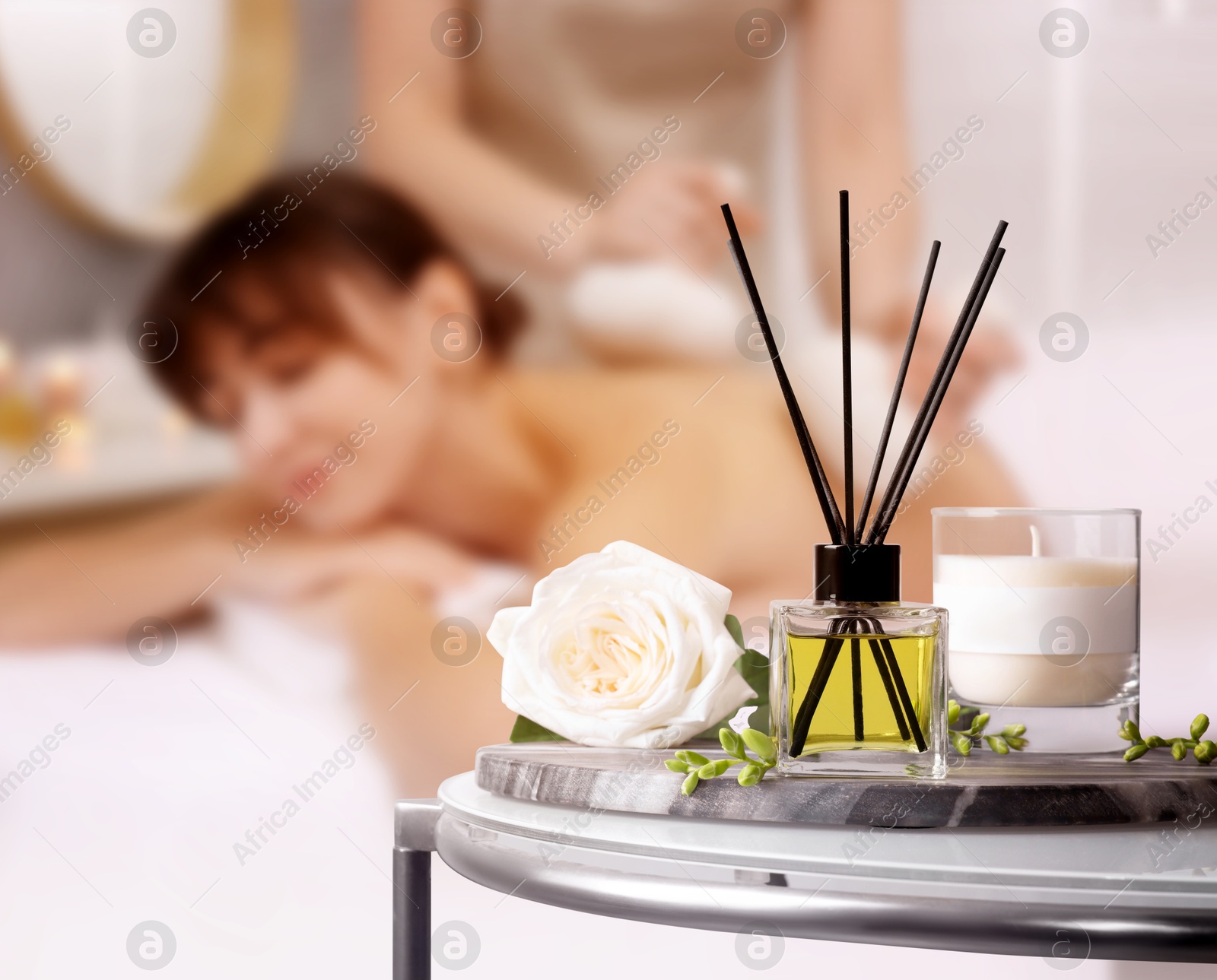 Spa therapy. Woman receiving massage on table and composition with aromatic reed air freshener in salon, selective focus Image of Spa therapy. Woman receiving massage on table and composition with aromatic reed air freshener in salon, selective focus