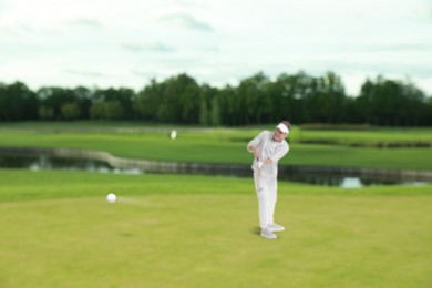 Image of Golfer hitting ball with club on course, selective focus