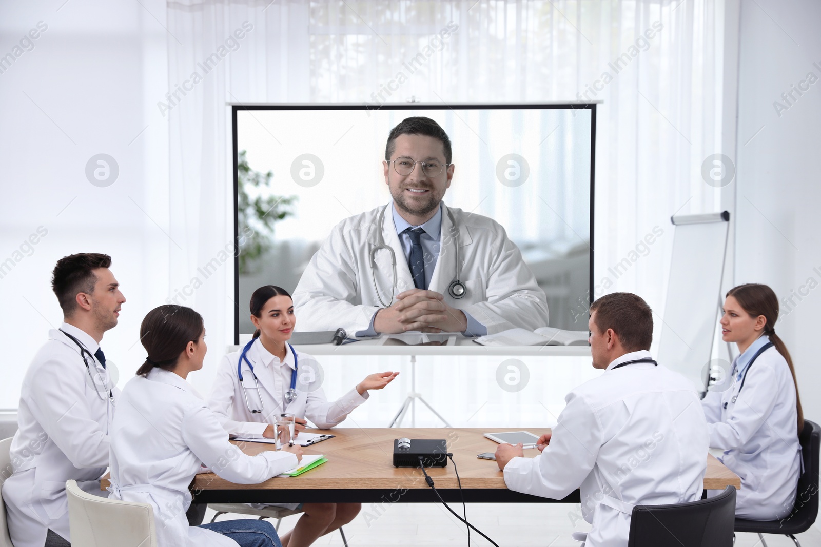 Team of doctors using video projector during conference indoors. Speaker on projection screen Image of Team of doctors using video projector during conference indoors. Speaker on projection screen