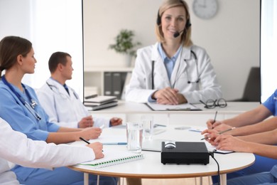 Image of Team of doctors using video projector during conference indoors. Speaker on projection screen