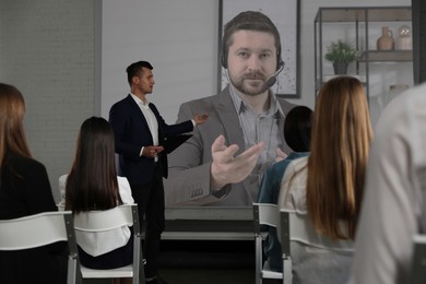 Image of Group of people participating in business conference indoors. Speaker on projection screen