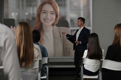 Image of Group of people participating in business conference indoors. Speaker on projection screen
