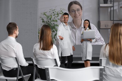 Image of Team of doctors using video projector during conference indoors. Speaker on projection screen