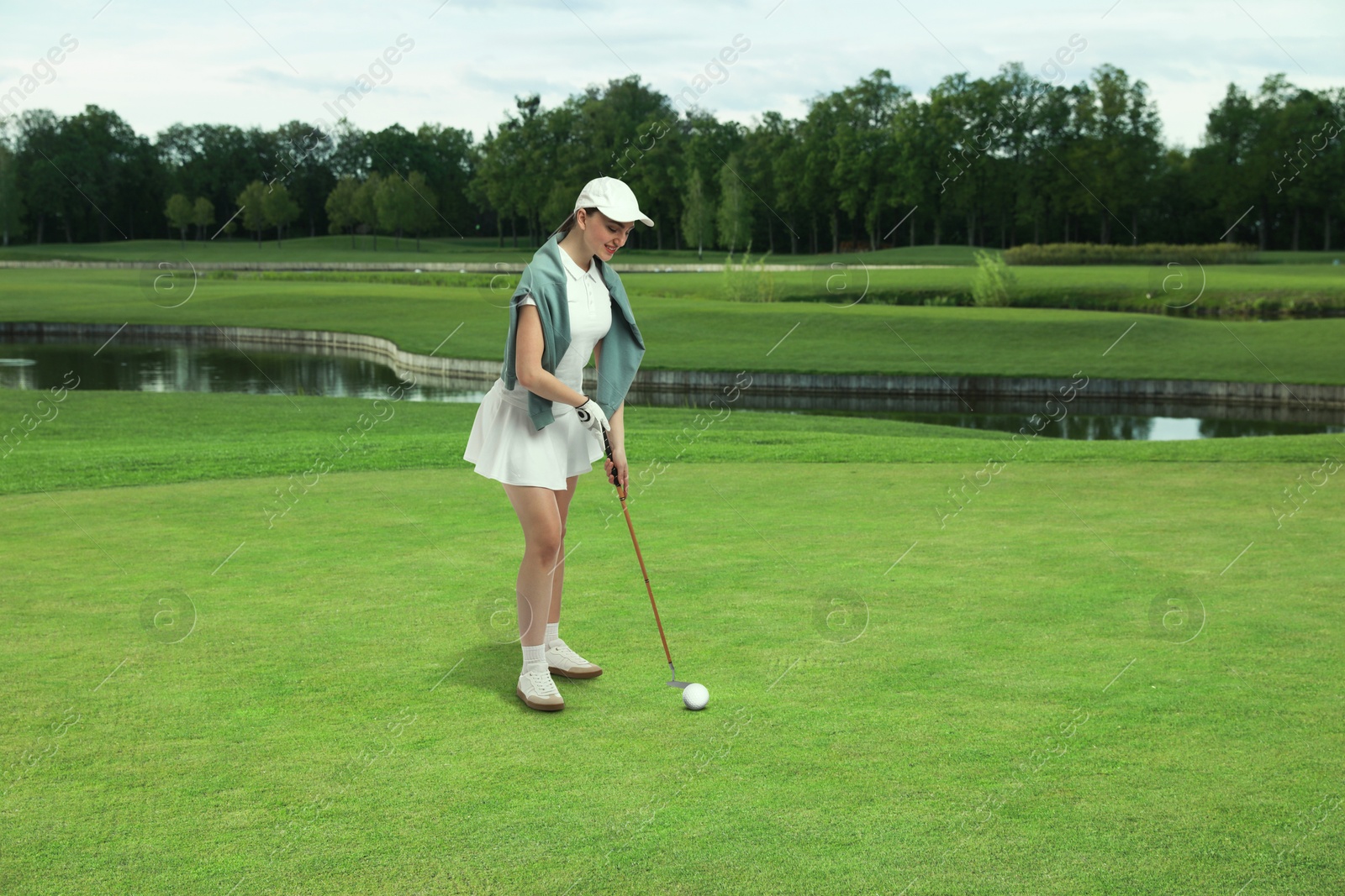 Woman with club playing golf on green course Image of Woman with club playing golf on green course
