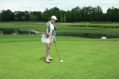 Image of Woman with club playing golf on green course