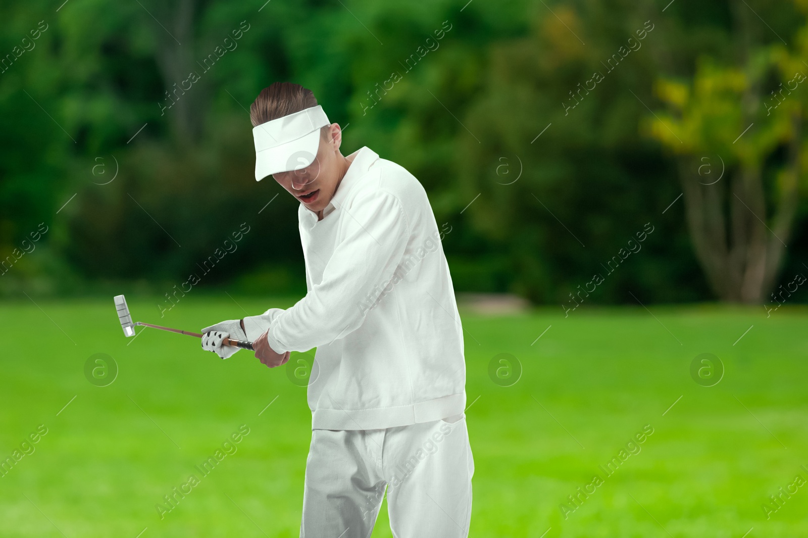 Man with club playing golf on green course Image of Man with club playing golf on green course