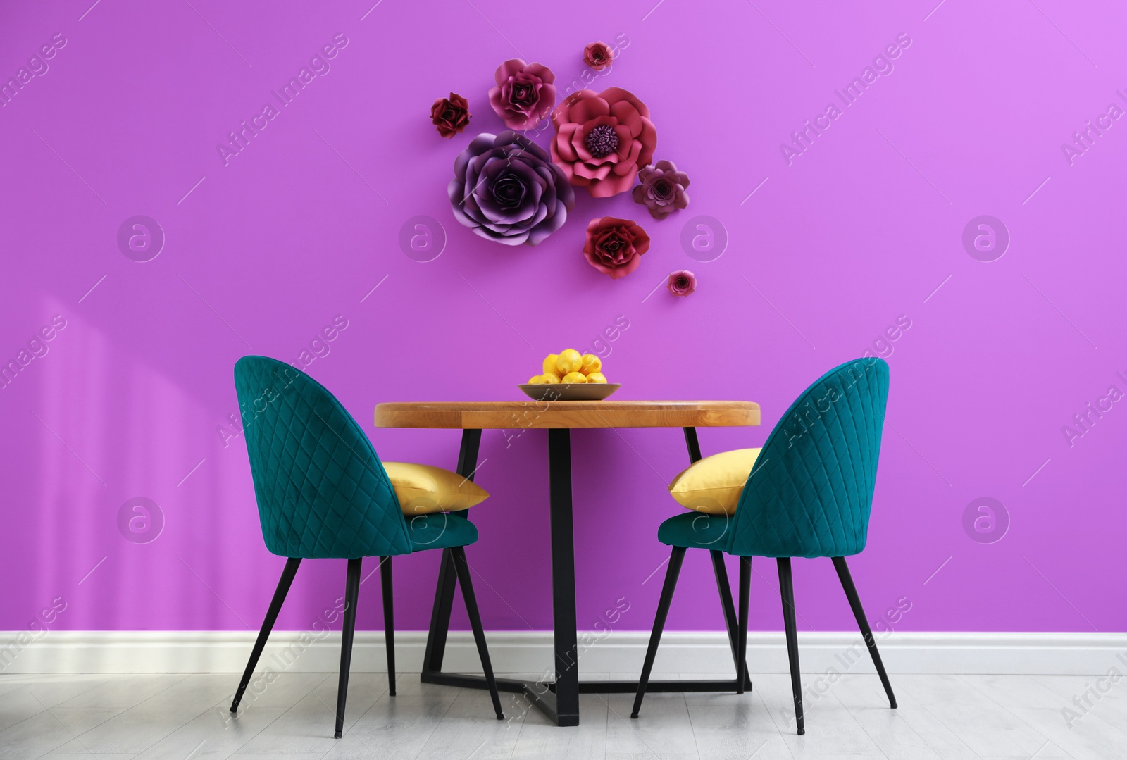 Dining table and blue chairs near violet wall with floral decor in room. Interior design Image of Dining table and blue chairs near violet wall with floral decor in room. Interior design