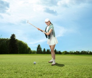 Image of Woman with club playing golf on green course