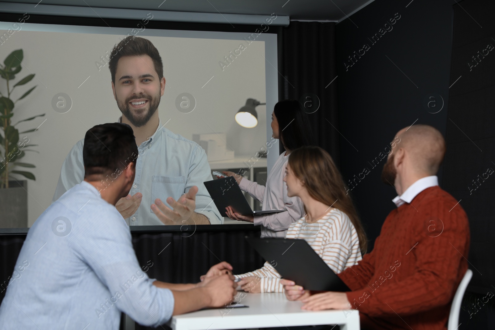 Group of people participating in business conference indoors. Speaker on projection screen Image of Group of people participating in business conference indoors. Speaker on projection screen