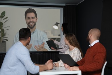 Image of Group of people participating in business conference indoors. Speaker on projection screen