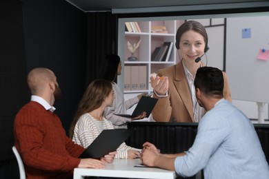 Image of Group of people participating in business conference indoors. Speaker on projection screen