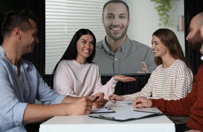 Image of Group of people participating in business conference indoors. Speaker on projection screen