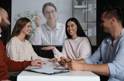 Image of Group of people participating in business conference indoors. Speaker on projection screen
