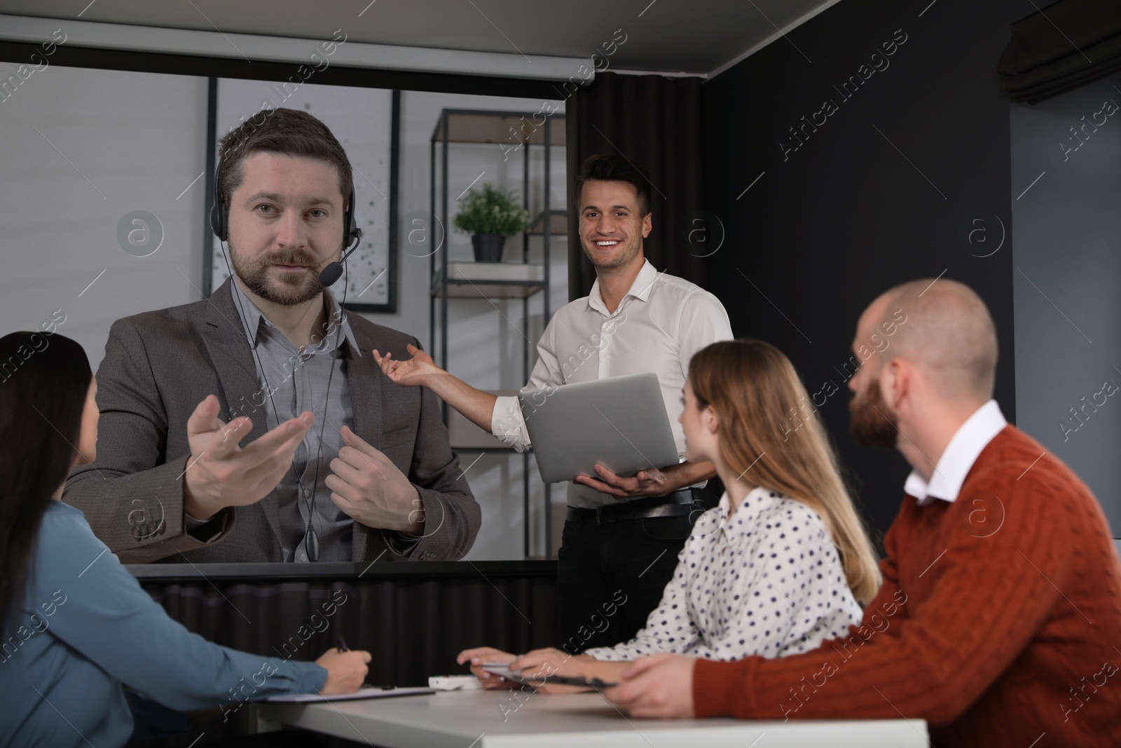 Group of people participating in business conference indoors. Speaker on projection screen Image of Group of people participating in business conference indoors. Speaker on projection screen