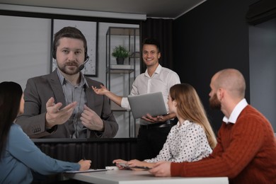 Image of Group of people participating in business conference indoors. Speaker on projection screen
