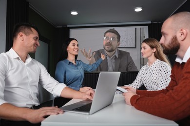 Image of Group of people participating in business conference indoors. Speaker on projection screen